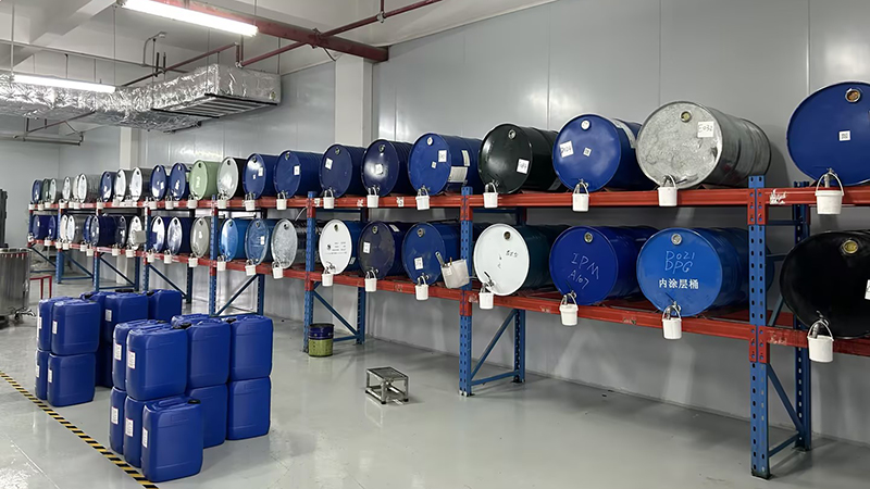 Industrial warehouse interior with neatly arranged barrels for Aroma Diffuser Oil storage multi-layered red and blue metal shelves blue black green silver labeled barrels IPN 8710 inner coating barrel small white sampling buckets gray floor yellow black warning lines fluorescent lights ventilation ducts Aromaprox professional manufacturer home fragrance waterless diffuser aromatherapy air freshener air diffuser fragrance marketing aroma marketing scent marketing Aroma Diffuser Oil Wholesaler Supplier Manufacturer Factory Company Custom Wholesale OEM ODM commercial scent diffuser hotel scenting solution